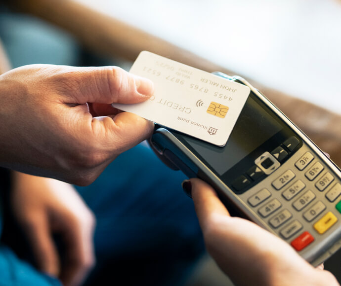 Close-up of a hand holding a credit card to a card reader