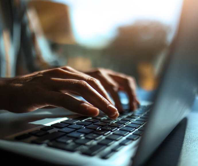 Close-up of hands typing on a laptop